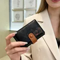 Close-up of black textured trifold wallet featuring a cute cat illustration held by a model - Black