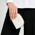 Close-up of semi-circle white leather coin purse with silver zipper and classic star logo - Off-white