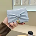 Petit portefeuille en cuir brillant bleu clair avec un nœud et un pendentif doré - Bleu