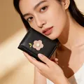 Gros plan du mini portefeuille matelassé noir avec broderie florale rose et feuille - Noir