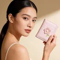 Gros plan d'un mini portefeuille rose matelassé avec broderie florale à la main - Rose Clair