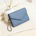 Blaue Briefumschlag-Geldbörse mit Litschi-Muster und Silberkette auf Strickdecke - Graublau
