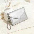 Detail der silbernen Mini-Geldbörse mit Litschi-Maserung und Kette auf weißem Strick - Silber