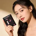 Close-up of small black leather wallet with cherry bow print held by a model - Black