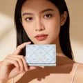 Close-up of light blue bow wallet with sweet girl metal plate held by a model - Pale Blue