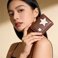 Brown short tri-fold star wallet with white star patches held by a model - Coffee
