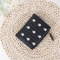 Short black bifold wallet featuring white daisy embroidery and gold zipper detail - Black