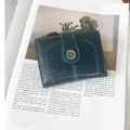 Close-up of vintage dark teal faux leather wallet with hollow patterns and daisy clasp - Teal