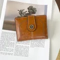 Close-up of vintage brown leather wallet with floral button and cutout details on magazine - Brown