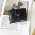 Detail of vintage black faux leather wallet with daisy clasp and white stitching detail - Black
