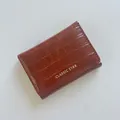 Cartera triple marrón caramelo con textura de piedra y detalle de logotipo dorado - Marrón