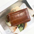 Porte-cartes marron motif crocodile avec fermeture dorée et lanière sur un magazine - café