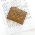 Petit portefeuille marron matelassé avec zip doré et plaque sur un livre rétro - Marron