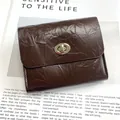 Deep brown crackle texture wallet with silver twist lock on a vintage magazine background - Coffee