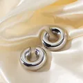 Macro shot of polished silver chunky C-shaped hoop earrings on champagne silk fabric - Silver Style (JC24310-3-2)