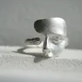 Vue macro d'une bague masque en argent mat sur pierre blanche avec anneau ouvert ajustable - Argent