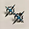 Macro detail of gothic cross earrings with bright blue gemstones in black metal finish - Stud Earrings