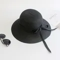 Black straw sun hat with ribbon bow and wide brim shown with travel magazine - Size M (Adult 56-58cm) / Black