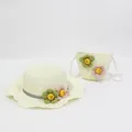 Detail of straw hat and matching bag set with wavy brim and floral decorations - Cream