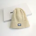 Berretto in maglia a trecce per adulti color crema con una toppa con lettera VE - Taglia unica / Beige