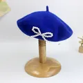 Detailansicht der Wollbaskenmütze in Kobaltblau mit verzierter weißer Perle-Schleife - S Kinder (49-52cm) / Königsblau