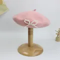 Detail der rosa Wollbaske mit dekorativer Perllenschleife auf einem Holzständer - S Kinder (49-52cm) / Rosa