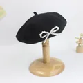 Detailansicht der schwarzen Wollbaske mit eleganter Perlen-Schleife auf einem Hutständer - S Kinder (49-52cm) / Schwarz