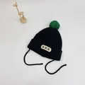Close-up of black ribbed knit baby hat with green pompom and beige patch detail - S (48-52cm) / Black