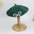 Detail von dunkelgrüner Wollbaskenmütze mit Schleife aus weißen Perlen an der Seite - Dunkelgrün