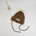Detail of kids knit beanie with ear flaps, pom-pom, and adjustable chin ties - S (48-52cm) / Coffee