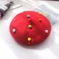 Rotes Kinder-Barett aus Wolle mit bunten Pompons verziert auf weißem Grund - S Kinder (48-52cm) / Rot