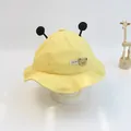 Close-up of yellow baby sun hat featuring cute plush pom-poms and a bear patch detail - Size S (46-48cm) / Yellow