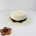 Close-up of a woven cream boater hat with a black bow ribbon on a minimal white background - S (52cm) / Cream