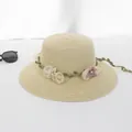 Detail eines Strohhuts mit dekorativer grüner Ranke und transparentem Blumenschmuck - Seidennetzblume Breite Krempe - Beige