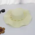 Detail eines cremefarbenen Strohhutes mit Perlenband und natürlich gewellter breiter Krempe - M (Erwachsene) / Holzperle Muschelrand / Creme