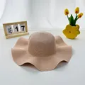 Detail of a beige woven straw sun hat with a wavy wide brim and fine summer texture - S Kids / Pink
