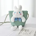 Detail of light green straw crossbody bag featuring a large plush bunny with blue eyes - Green Bag White Rabbit