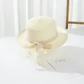 Detailed view of beige flat top straw hat featuring delicate lace bow on white table - S Kids Size / Cream
