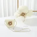 Dettaglio del cappello di paglia e borsa a tracolla coordinata con decorazioni floreali - Crema