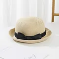 Close-up of kids straw sun hat with black ribbon bow on a clean white surface - Beige