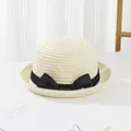 Close-up of cream children straw hat featuring a chic black ribbon bow and woven texture - Cream