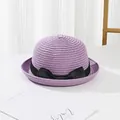 Close-up of lilac straw hat with black bow ribbon on a minimalist white background - Purple