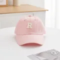 Detailansicht der rosa Baumwoll-Baseballkappe mit weißem R-Stick auf einem weißen Tisch - S Kinder (48-52CM) / Rosa