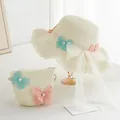 Detailed view of woven straw hat and matching bag with lace butterfly accents and pearls - Cream