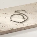 Détail macro du bracelet à chaîne gourmette avec barre gravée 'you complete me' - Couleur Acier Modèle Femme