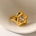 Nahaufnahme des matten goldenen Blumenrings mit Zirkonsteinen auf Keramiktablett - US 6 / Gold Weißer Zirkonia