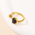 Primer plano detallado de un anillo abierto dorado con piedra negra y textura irregular - US 6 / Dorado Piedra de Ojo de Gato Negra