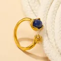 Detailed shot of open cat claw ring featuring dark blue gemstone on a neutral background - Gold Lapis Lazuli