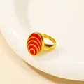 Detailansicht eines ovalen vergoldeten Rings mit roten Emaille-Konzentrik-Mustern - US 6 / Gold Rot Öltropfen