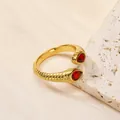 Vue détaillée de la bague en acier doré 18 carats avec texture spirale et zircon rouge - Or Rouge
